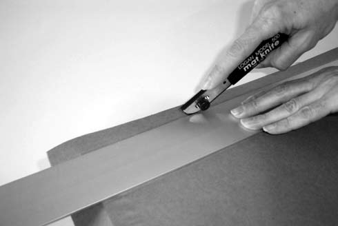 Figure BB-5: Use a straightedge and mat knife to trim the paper to the edge of the frame.